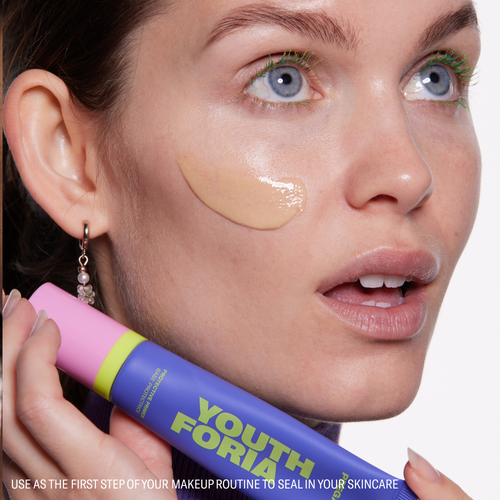 Woman using youthforia pregame primer with swatch on face